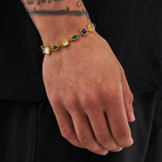 Gold bracelet with colored stones on a wrist against a black background