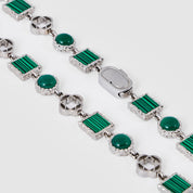 Silver bracelet with green gemstones on a white background